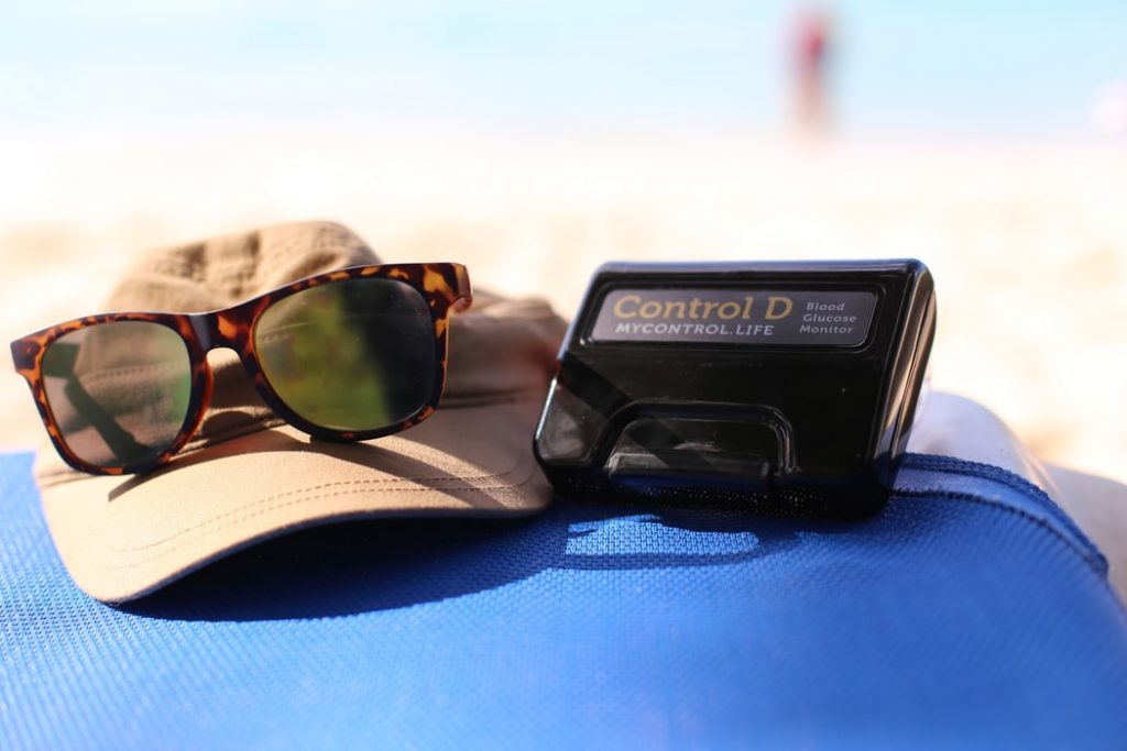 Sleep apnea can affect diabetes, hat, sunglasses, and glucometer with the beach in the background