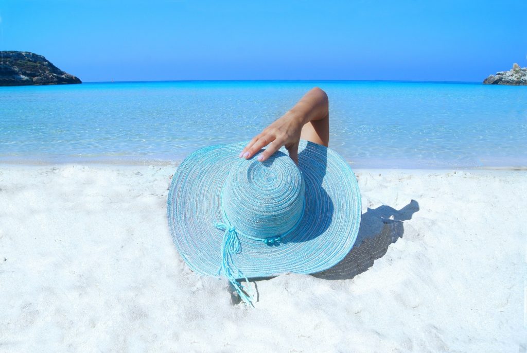 Sleepy sunshine, woman laying on a beach with a blue sunhat