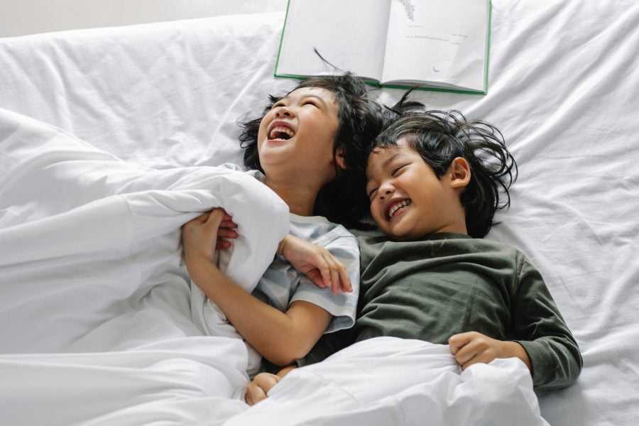 The connection between children's mental health and sleep, two children laughing in bed