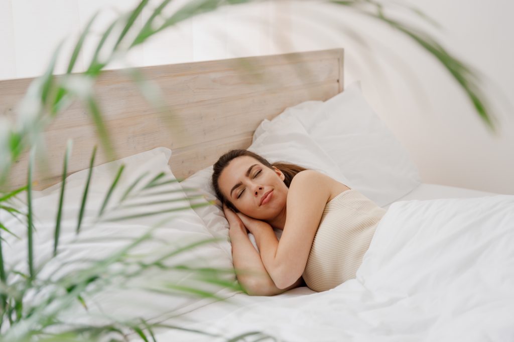 A happy young woman with a peaceful expression wearing casual clothes and smiling warmly towards the camera. She has a relaxed demeanor and appears content. How Your Sleep Habits Can Impact the Planet on Earth Day