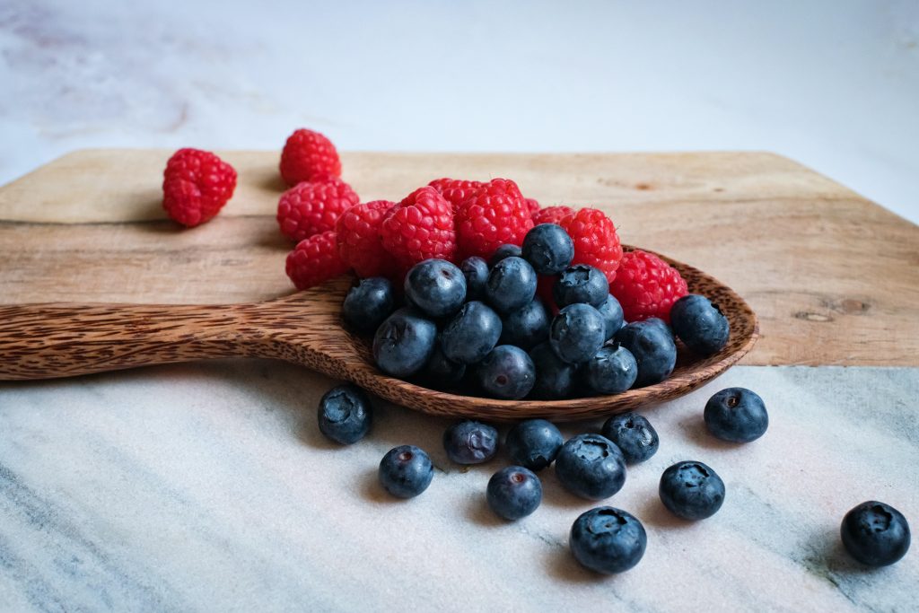 A wooden spoon holds a delectable arrangement of plump blueberries and vibrant raspberries.