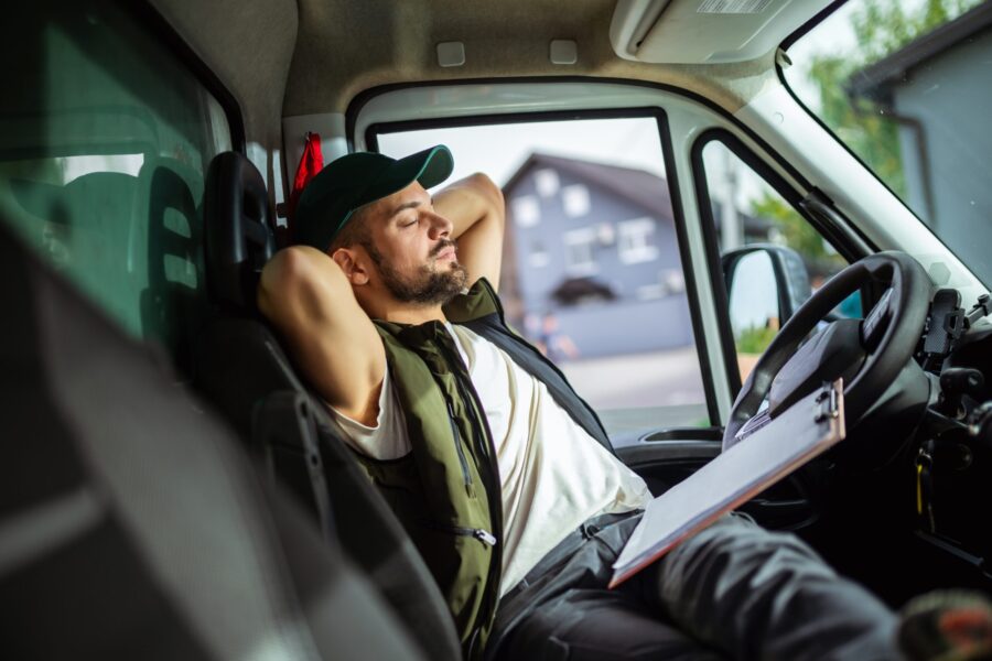 A tired truck driver takes a break from driving and rests in his truck. The Dangers of Sleep Apnea in Truck Drivers